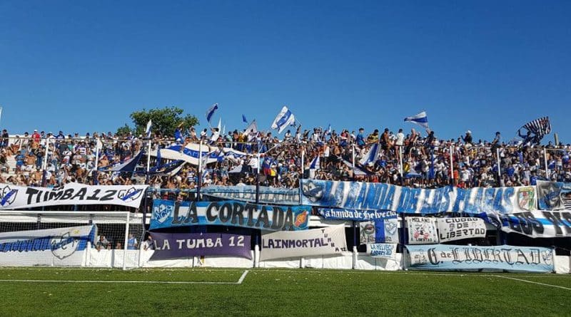 Hinchada del Club Atlético Midland con banderas de "La Tumba 12" y "La Cortada" en la tribuna popular, representativo de los Funebreros de Libertad en el fútbol argentino. Créditos: Sector Prensa