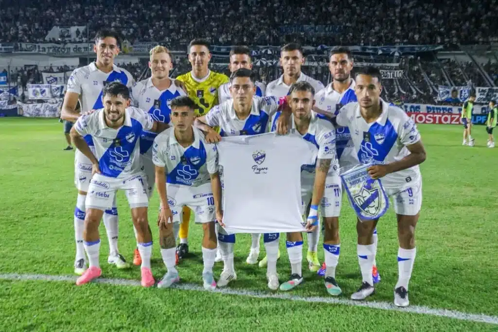 Formación titular de Midland sosteniendo una camiseta en homenaje a Jorge Payare en la previa del partido contra Quilmes por la Primera Nacional el 21 de febrero de 2026.