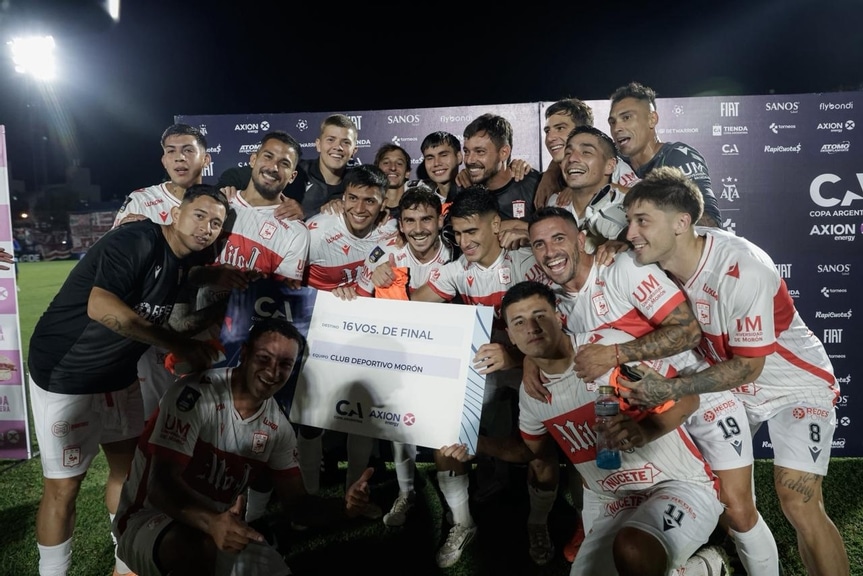 Jugadores del Club Deportivo Morón celebran en el campo de juego tras clasificar a los 16vos de final de la Copa Argentina. Sostienen un cartel oficial del torneo que confirma su pase a la siguiente ronda, donde enfrentarán a Midland