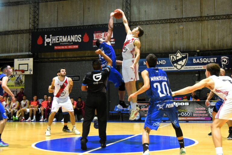 Salto inicial en un partido de básquet de Midland en Libertad. Se observa la disputa del balón en las alturas, con el escudo de "Midland Basquet" y la publicidad local de fondo.